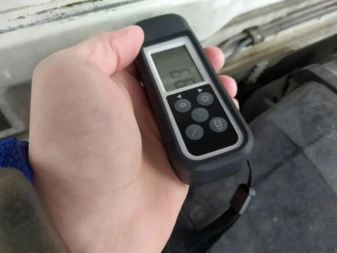 Close view of man's hand testing the thickness of the car paint Stock Photos