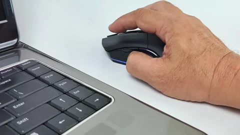 Close-up view of a man's hand using a wireless computer mouse on a desk, sc.. 스톡 동영상 338326129