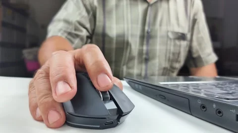 Close-up view of a man's hand using a wireless computer mouse on a desk, sc.. 스톡 동영상 338326591