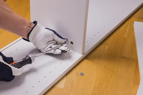 Close up view of man's hands assembling white furniture in an apartment. Foto stock