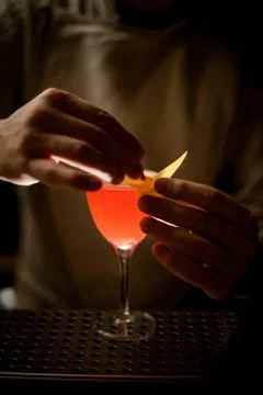 Close-up view on man's hands decorates glass with bright red cocktail by fresh Fotos Stock