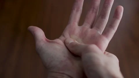 Close-up view of a man's hands performing a therapeutic self-massage on the palm Stock Footage 327158348