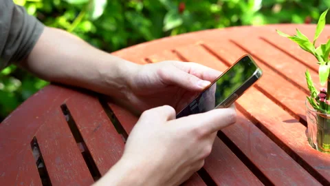 Close-up view of a man's hands scrolling through his phone Stock Footage 234401022