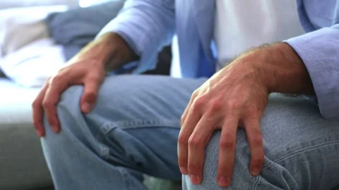 Close up view of a man's hands tapping his knees nervously while sitting on a Stock Footage 344781939