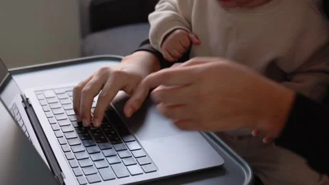 Close up view of man's hands typing on laptop while cute toddler boy disturbs Stock Footage 244828764