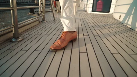 Close view of a man's legs in orange boots walking on a wooden deck boat Stock Footage 212389558
