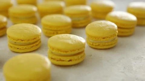 Close-up view of many rows of yellow lemon macarons macaroon on white background Stock Footage 130237476