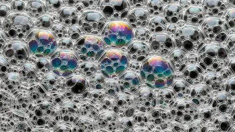 Close up view of many soapy bubbles with rainbow reflections on a dark back.. Fotos de archivo