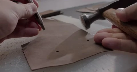 Close up view of master makes holes in leather piece to make shoes in 4k Stock Footage 200127213
