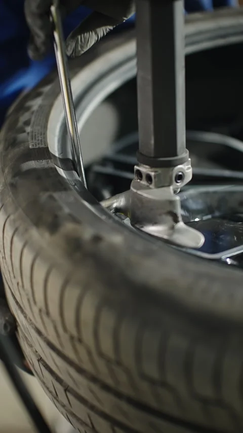 Close-up view of a mechanic mounting a car tire onto an alloy rim using a tire Video stock 334179552