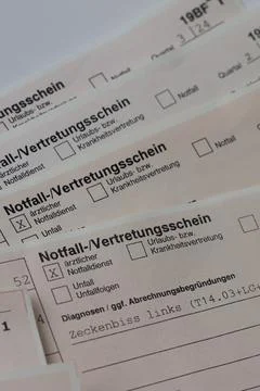A close-up view of medical forms titled 'Notfall-/Vertretungsschein' with c.. Stock Photos