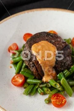 Close up view of a medium rare mignon steak, roasted with green beans and fre Stock Photos