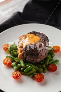 Close up view of a medium rare mignon steak, roasted with green beans and fre Stock Photos
