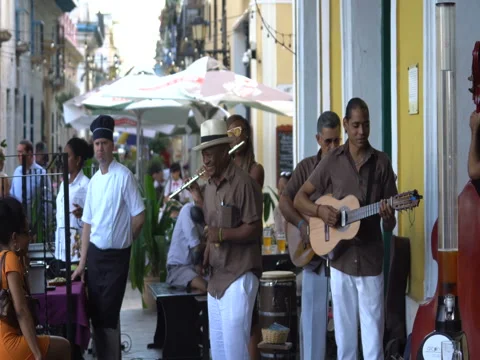 Close-up view men musicians dressed in white trousers, hat and brown shirt play Stock Footage 69759356
