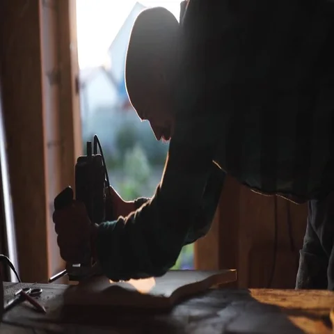 Close-up view of men working with electric jigsaw and wooden plank. sun flare on Stock Footage 69540312