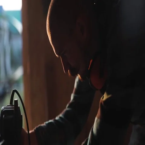 Close-up view of men working with electric jigsaw and wooden plank. sun flare on Stock Footage 69540506