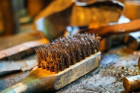 A close-up view of a metalworking workshop featuring a wire brush on a workbench Stock Photos