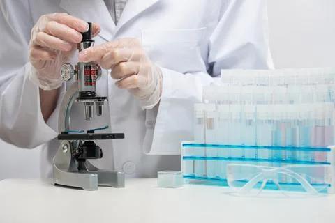 Close-up view of microbiologist in protective gloves explore with microscope  Stock Photos