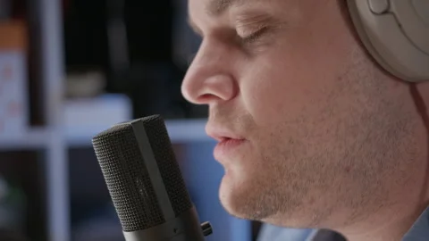 Close up view of microphone and face of man in blue shirt singing in recording Stock Footage 243775708