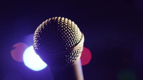 Close-up view of a microphone lighted by a light beam standing on a stage with Stock Footage 248768120