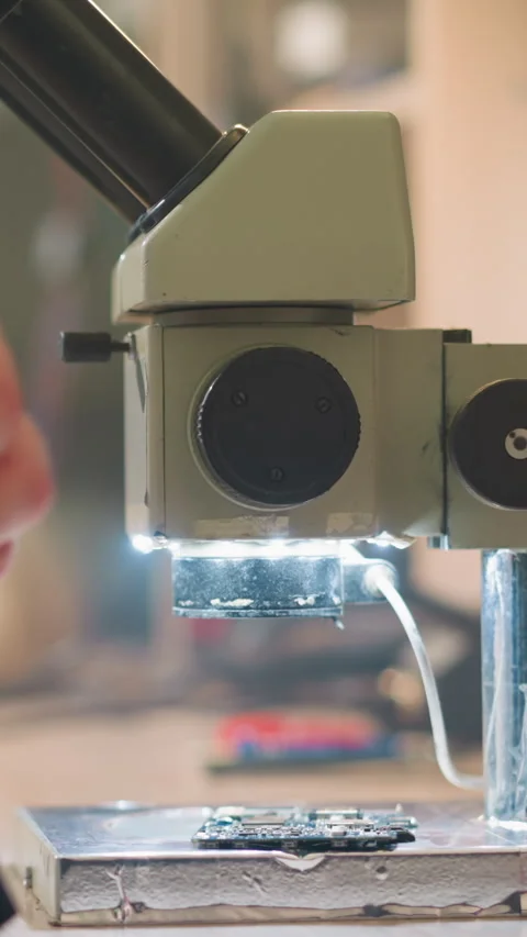 Close-Up View of Microscope and Circuit Board with Scientist Preparing for Stock Footage 310491163