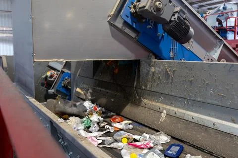 Close view of mixed waste on conveyor belt inside recycling sorting facility Stock Photos
