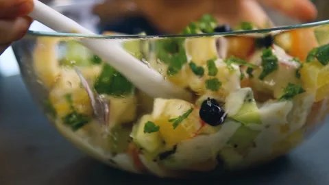 Close up view of mixing fresh fruit salad with apples, oranges, kiwi, tangerines Video stock 136823040
