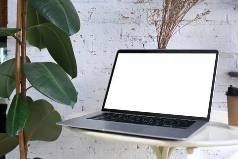 Close up view of mock up computer laptop with white screen on white desk at m Stock Photos