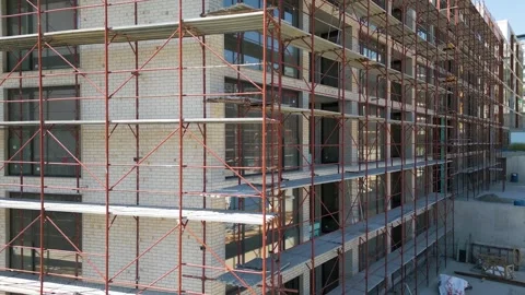 Close-up view of modern building facade under construction with red scaffolding Stock Footage 308378302
