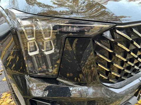 Close-up view of modern car headlight and grille design, showcasing sleek lines Stock Photos