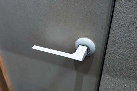 Close-up view of a modern door handle on a textured gray wall, showcasing sleek Photos