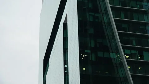 Close-up view of a modern glass skyscraper featuring a curved facade with green Stock Footage 327730031
