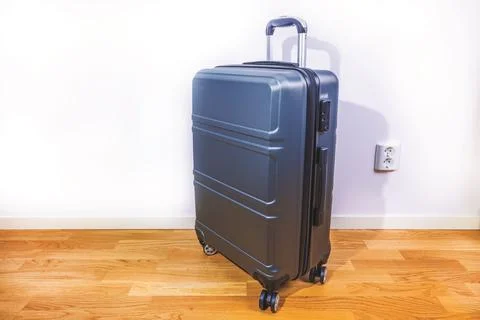 Close up view of modern hard shell suitcase standing on wooden floor Stock Photos