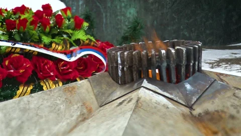 Close view of the monument of the eternal flame on the background of red flowers Stock Footage 136705485