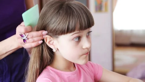 Close up view of mother combing her daughter�s hair, while little girl putting Stock Footage 99312347