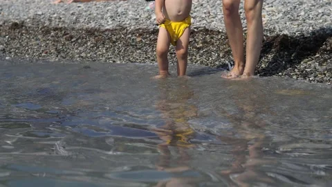 Close up view of mother helping 2 years old son in yellow swim trunks to go onto Stock Footage 219596185