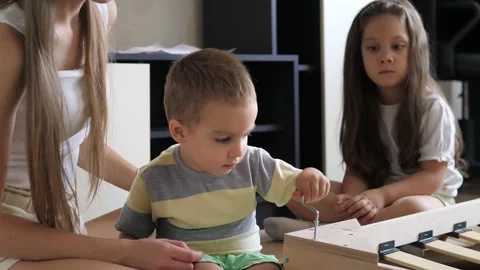 Close up view of mother with kids assembling wooden parts of an orthopedic base Stock Footage 204894299