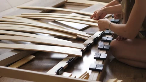 Close up view of mother with kids assembling wooden slats of an orthopedic base Stock Footage 248309664