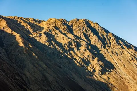 Close up view of a mountain side under direct evening sun light with clear blue Photos