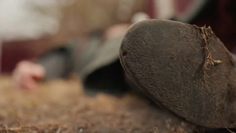 Close view of mud-covered boot sole in foreground beside prone person lying on Stock Footage 343683560