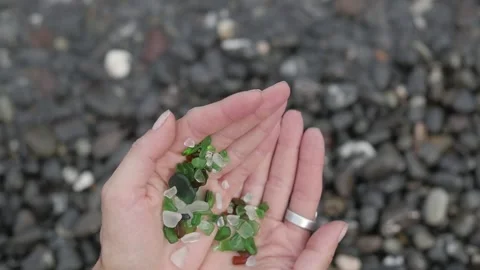 Close-up view of multi-colored glass passing through the woman's hands against Stock-Footage 149423689
