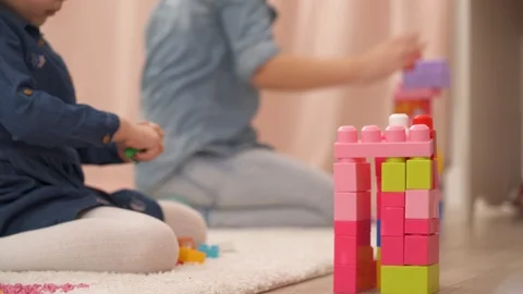 A close-up view of a multicolored toy tower. Little girls build a tower of Stock Footage 105372563