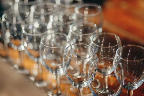 A close-up view of multiple empty wine glasses arranged in rows on a wooden Stock Photos