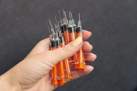 Close-Up View of Multiple Syringes Held in a Hand with a Distinct Orange Color Stock Photos