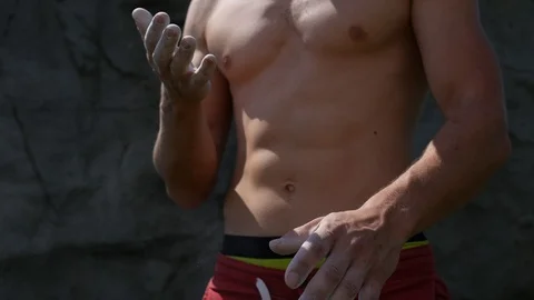 Close-up view of muscular man without shirt covering hands with white talc. Stock Footage 98654982