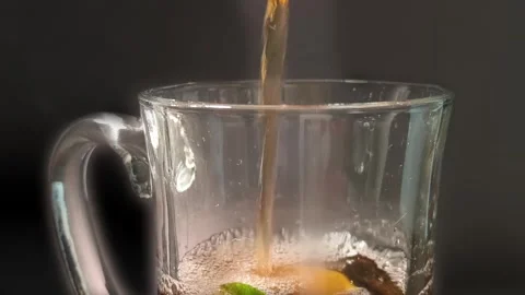 Close up view of nestea pouring into a clear glass cup mug with juicy green.. Video stock 318127534