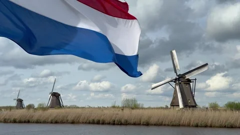 Close-up View to the Netherlands flag and wooden windmills at sunset Stock Footage 277433289