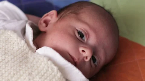 Close up view of a newborn baby looking to the camera while lying on his back on Video stock 168697376