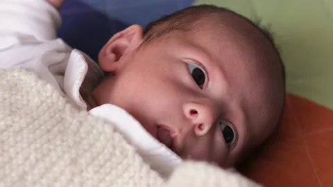 Close up view of a newborn baby looking curious to the side while lying on his Video stock 168971696