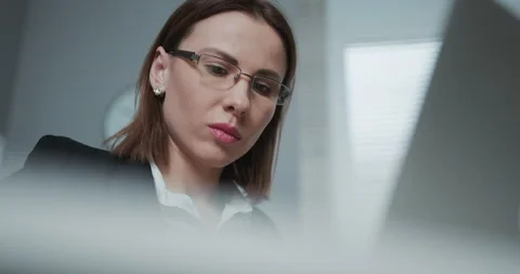 Close-up view of a nice focused woman wearing eyeglasses is working on her Stock Footage 194482749